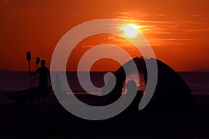 Silhouette family camping and kayaking on the beach with red sky sunset