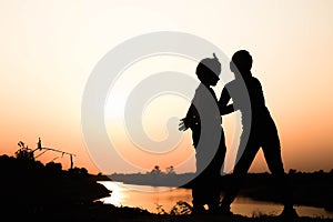 Silhouette of a family comprising a father, mother and two children happy family the sunset.Concept of friendly