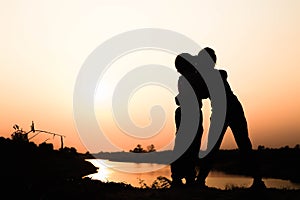 Silhouette of a family comprising a father, mother and two children happy family the sunset.Concept of friendly