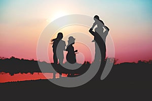 Silhouette of a family comprising a father, mother and two children happy family the sunset.Concept of friendly