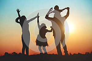 Silhouette of a family comprising a father, mother and two children happy family the sunset.Concept of friendly