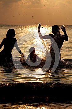 Silhouette Of Family Having Fun In Sea On Beach Holiday