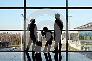 Silhouette of family with luggage near window