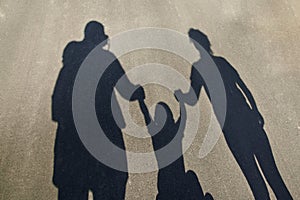 Silhouette of a family on the pavement: dad, mom and baby holding hands