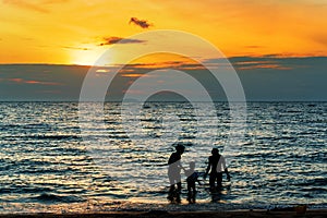 Silhouette of Family playing on the beach at sunset