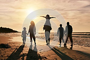 Silhouette, family is walking on beach and back view with ocean waves, sunset and bonding in nature. Generations, people