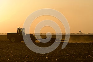 Silhouette of farmer tilling his land after the harvest.