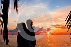 Silhouette of father and daughter on the beach at dusk.