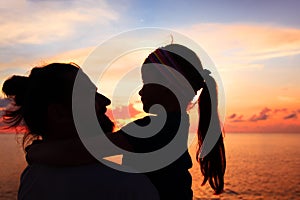 Silhouette of father and daughter on the beach at dusk.