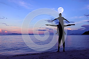 Silhouette father and daughter on the beach with the moon and bl