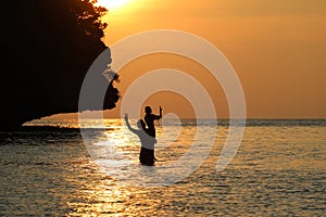 Silhouette Father and daughter enjoy swimming and snorkeling near the beach with sunset