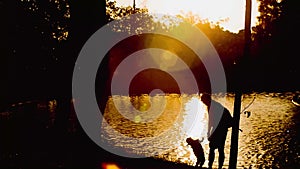 Silhouette of father daughter or  son watching the sunset at Lake . Father and son are playing on the lake at sunset