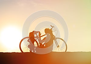 Silhouette of father and little daughter biking at sunset