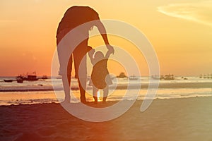 Silhouette of father and little daughter walk at sunset