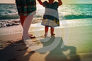 Silhouette of father and little daughter walk at sunset