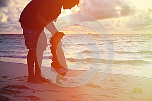 Silhouette of father and little daughter walking at sunset