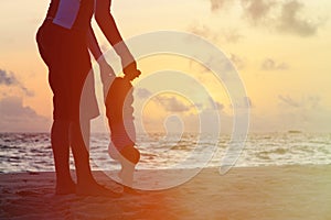 Silhouette of father and little daughter walking at sunset