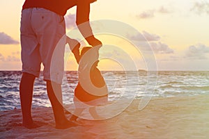 Silhouette of father and little daughter walking at sunset