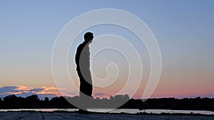 Silhouette of father and son with a bike communicating on the background of the morning sky on the bank of the river or lake. A ha