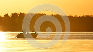 Silhouette of father and son fishing on lake at sunset.