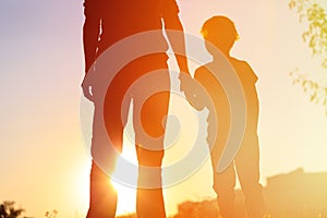 Silhouette of father and son holding hands at