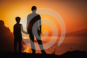Silhouette of father and son holding hands in sunset nature