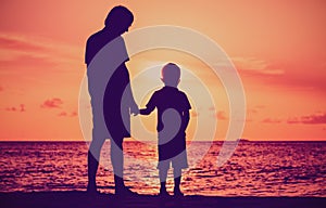 Silhouette of father and son holding hands at sunset sea