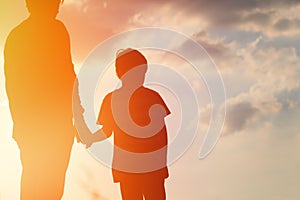 Silhouette of father and son holding hands at sunset