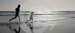 Silhouette of father and son run on summer beach outdoor, banner poster with copy space, dad and child silhouettes