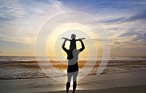 Silhouette father were riding neck carries daughter look out at the sea at sunset