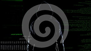 Silhouette of fearless male hacker standing on animated computer code background