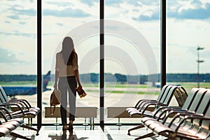 Silhouette of female airline passenger in an airport lounge waiting for flight aircraft