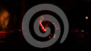 The silhouette of a female dancer holding jewelry in the dark of night is lit by the light of a burning fire