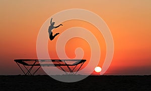 Silhouette of female gymnast jumping on trampoline