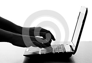 Silhouette of a female hands typing on the keyboard of the netbook