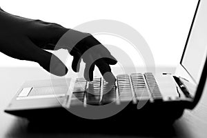 Silhouette of a female hands typing on the keyboard of the netbook