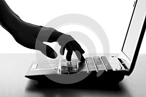 Silhouette of a female hands typing on the keyboard of the netbook