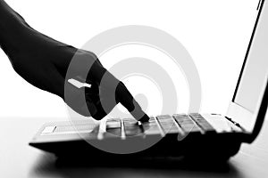 Silhouette of a female hands typing on the keyboard of the netbook