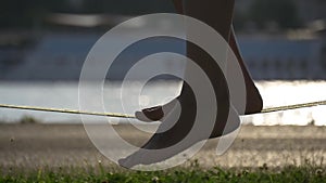 Silhouette of female legs on a slackline rope