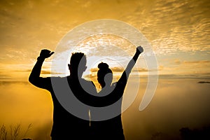 Silhouette of a female and male holding hands at sunrise
