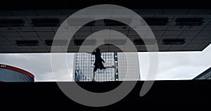 Silhouette female person jumping in dark underground station or parking.