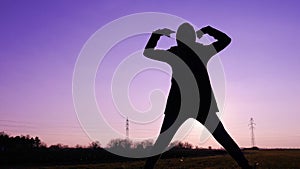 Silhouette of a female posing against the purple sky at sunset - confidence and strength concept