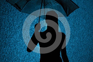 Silhouette of the figure of a young girl with an umbrella in the rain, a young woman with hand-picked hair is happy to drops of