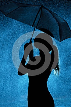 Silhouette of the figure of a young girl with an umbrella in the rain, a young woman is happy to drops of water