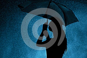 Silhouette of the figure of a young girl with an umbrella in the rain, a young woman is happy to drops of water, concept weather