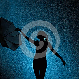 Silhouette of the figure of a young girl with an umbrella in the rain, a young woman is happy to drops of water, concept weather