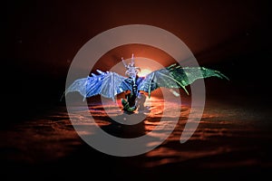 Silhouette of fire breathing dragon with big wings on a dark orange background. Horror image