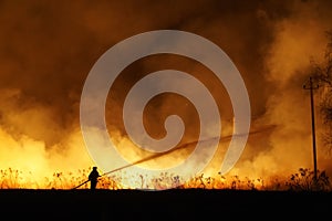 Silhouette of fireman fighting bushfire at night, man against the fire.