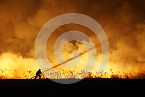 Silhouette of fireman fighting bushfire at night, man against the fire.