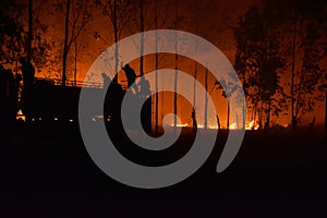 Silhouette of Firemen fighting a raging fire